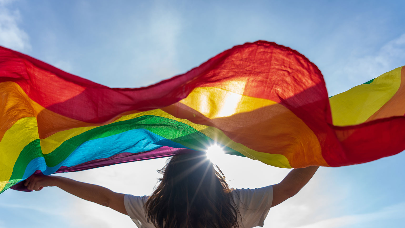Woman holding rainbow flag in sunlight